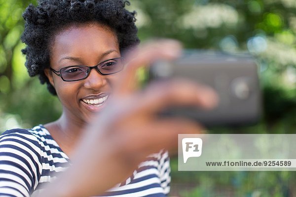 Junge Frau im Park nimmt Selfie auf Digitalkamera