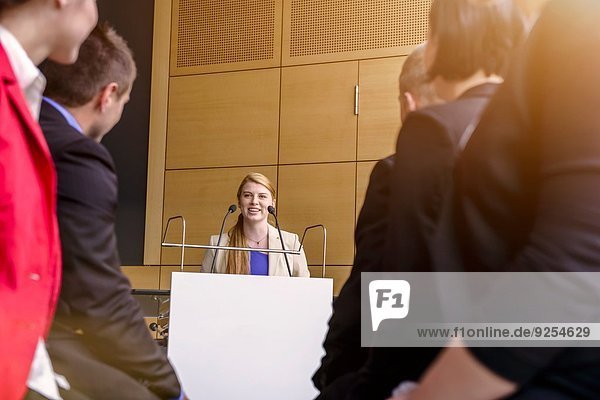 Young businesswoman speaking to audience in conference room