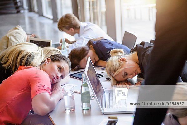 Businessmen and businesswomen exhausted at brainstorm meeting