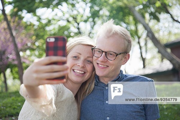 Junges Paar im Park nimmt Selfie mit Smartphone