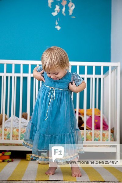 Weibliches Kleinkind bewundert ihr Partykleid im Schlafzimmer