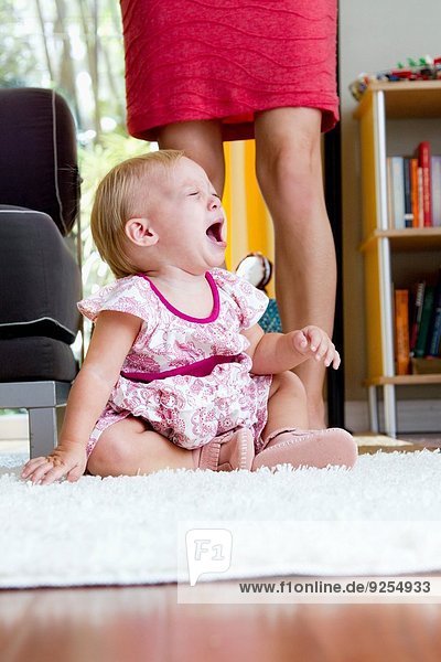 Legs of mid adult mother next to screaming baby daughter