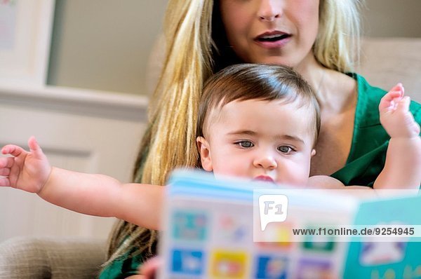 Mittlere erwachsene Mutter liest Bilderbuch zu Baby-Tochter