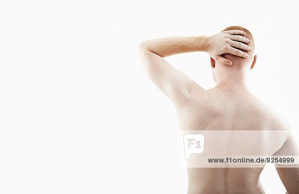 Rückansicht Atelierporträt eines jungen Mannes mit nacktem Rücken und Hand auf dem Kopf