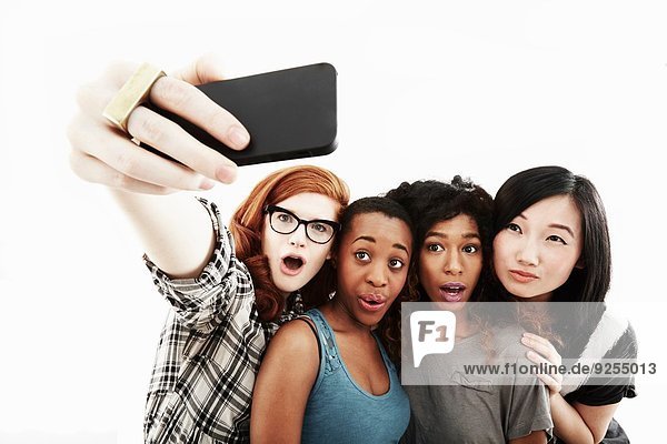 Studio-Porträt von vier jungen Frauen  die Selfie auf dem Smartphone nehmen