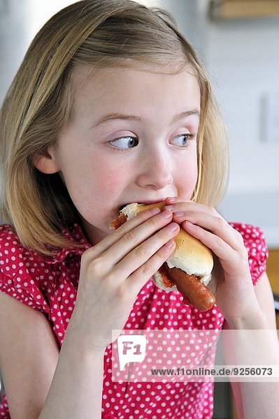 A little girl eating a hot dog