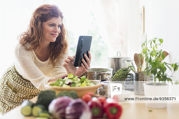 Woman cooking and using digital tablet in kitchen