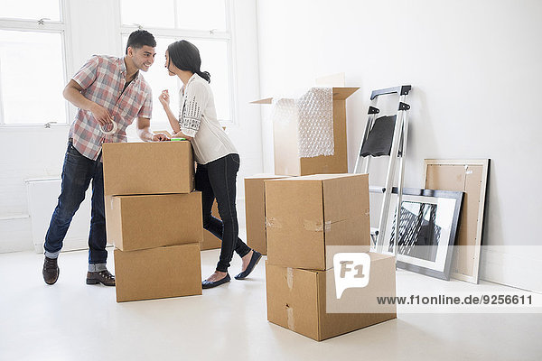 Young couple standing among boxes in new home