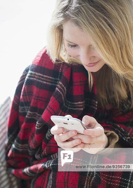 Woman wrapped in blanket text messaging