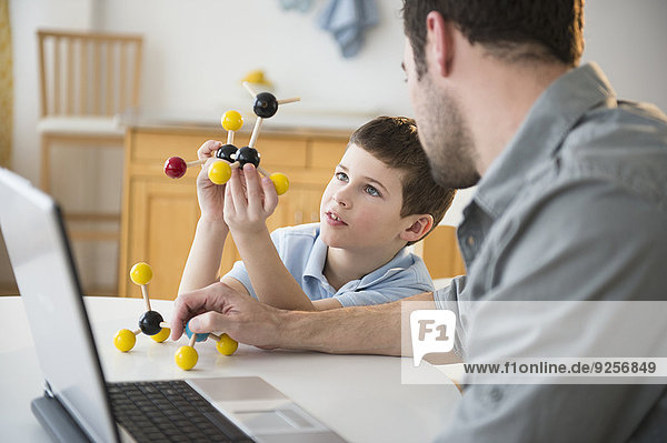 Father and son (8-9) looking at molecule model stack