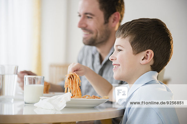 Father and son (8-9) eating spaghetti