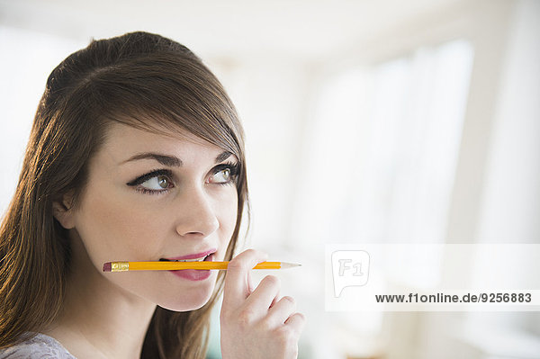 Young woman holding pencil in her mouth