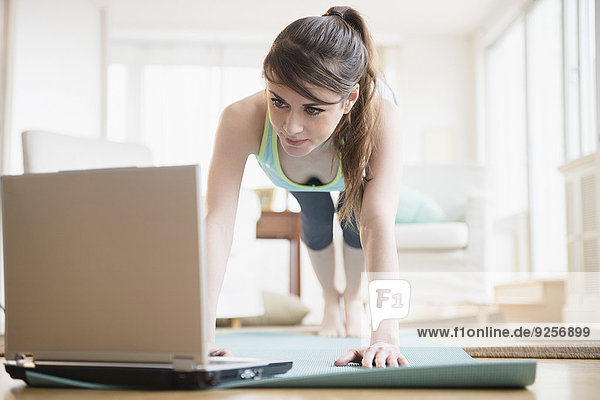 Young woman using laptop during exercising