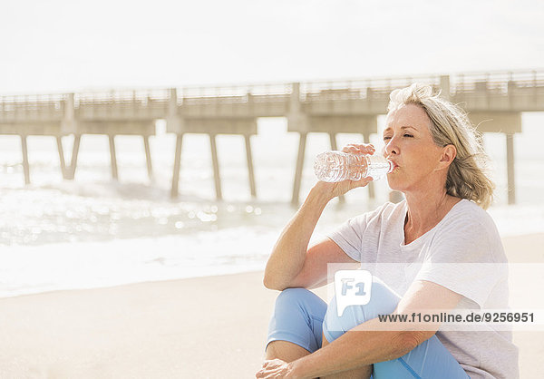 Senior woman drinking water on beach