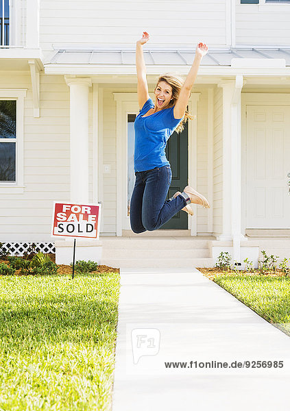 Woman jumping in front of new house