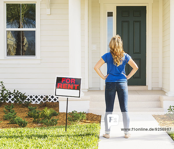 Rear view of woman standing next to for rent sign