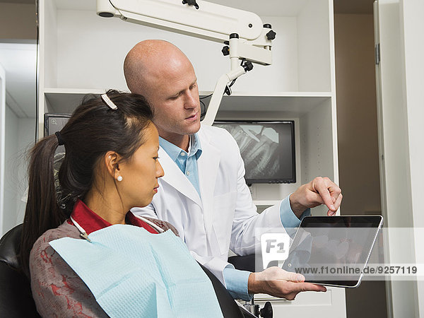 Dentist holding digital tablet with patient's x-ray