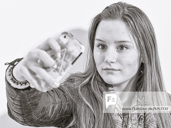 Caucasian teenage girl taking picture with cell phone