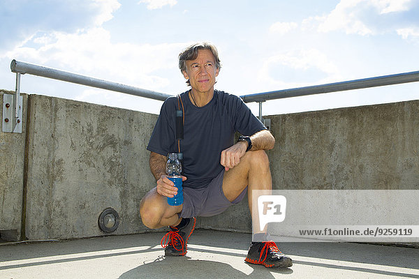 Caucasian runner resting on urban rooftop