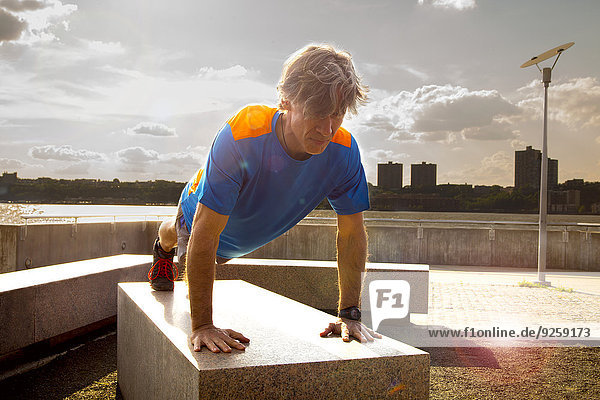 Caucasian man doing push ups in urban park