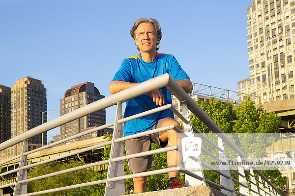 Caucasian man leaning on railing in urban park