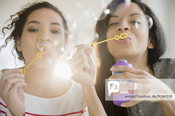 Mother and daughter blowing bubbles together