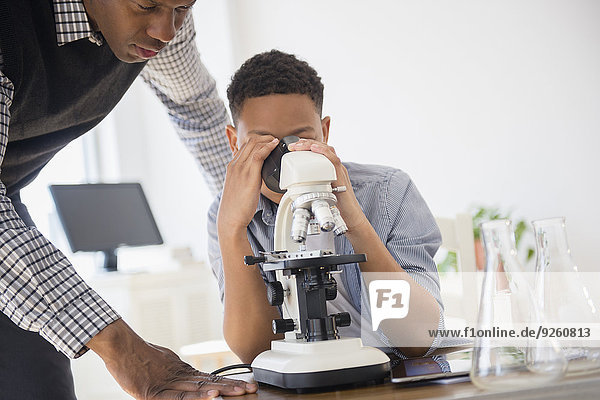 Teacher helping student use microscope in science class