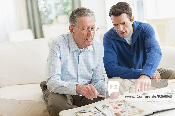 Caucasian father and son examining stamp collection