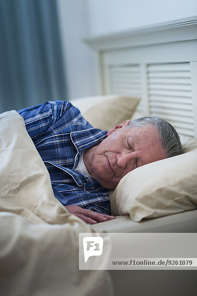 Senior Caucasian man sleeping in bed