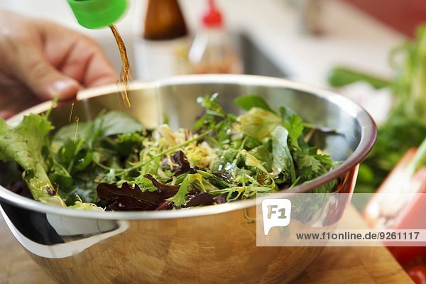 A fresh garden salad being drizzled with soy sauce