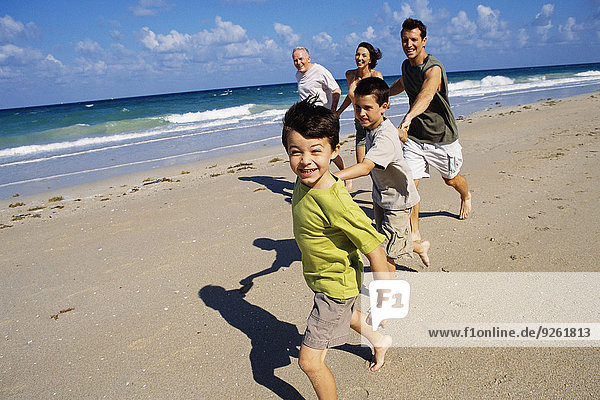 Caucasian family running on beach
