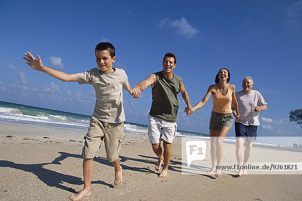 Caucasian family holding hands on beach