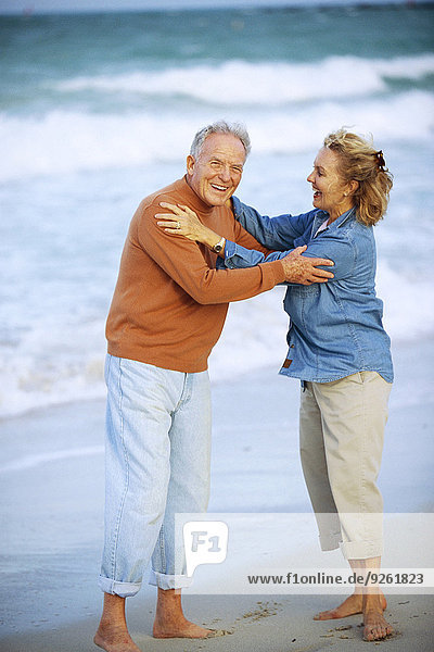 Senior Caucasian couple hugging on beach