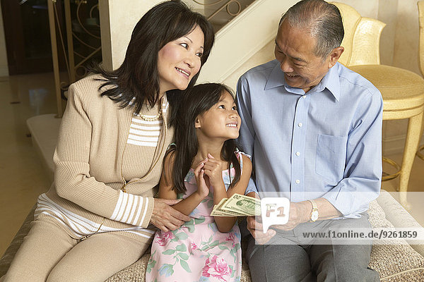Senior couple giving granddaughter money
