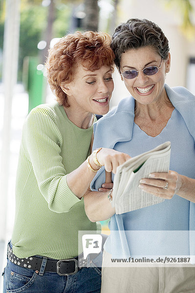 Senior women reading newspaper together