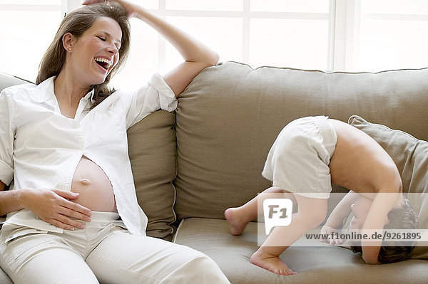 Pregnant mother and son playing on sofa