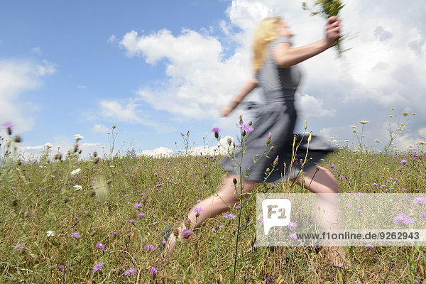 Junge Frau läuft auf Wildblumenwiese