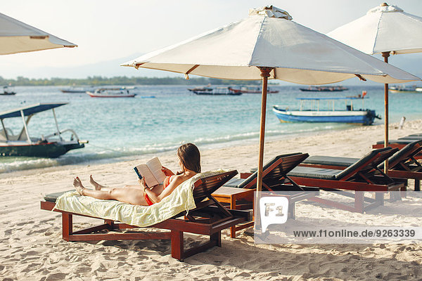 Indonesien  Gili-Inseln  Frau auf einem Strandkorb liegend  ein Buch lesend