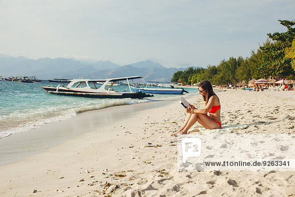 Indonesien  Gili-Inseln  Frau beim Lesen eines Buches am Strand