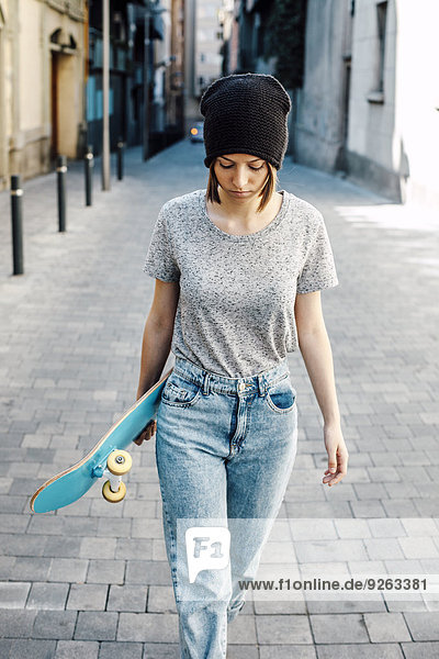 Porträt einer jungen Skateboarderin beim Gehen