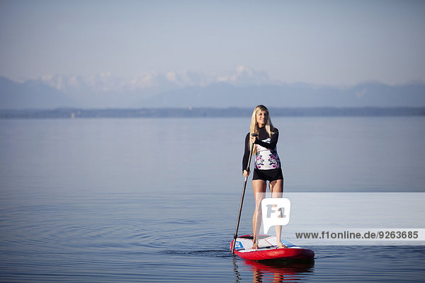 Deutschland  Bayern  junge Frau stehend auf Stehpaddelbrett am Starnberger See