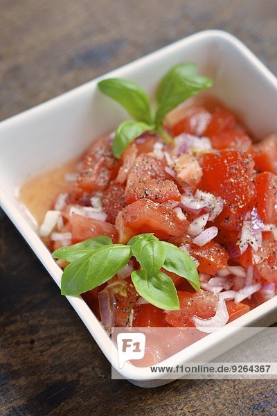 Tomatensalat mit Zwiebeln und garniert mit Basilikumblättern