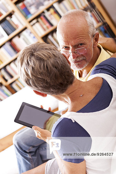 Seniorenpaar auf der Couch sitzend mit digitalem Tablett