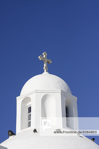 Griechenland,  Kykladen,  Santorini,  Kuppel mit Kruzifix einer weißen Kirche vor blauem Himmel