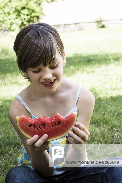 Lächelndes Mädchen beim Essen einer Wassermelone im Garten