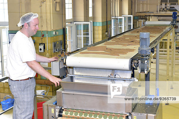 Germany  Saxony-Anhalt  man working at production line with dough in a baking factory