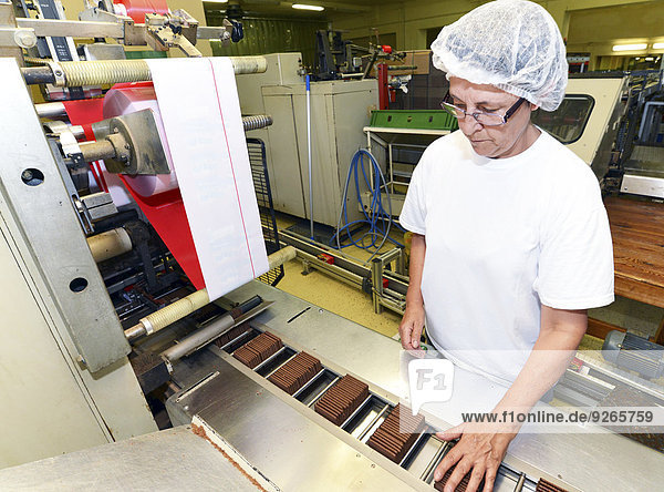 Deutschland  Sachsen-Anhalt  Frau steuert Verpackungsmaschine in einer Backfabrik