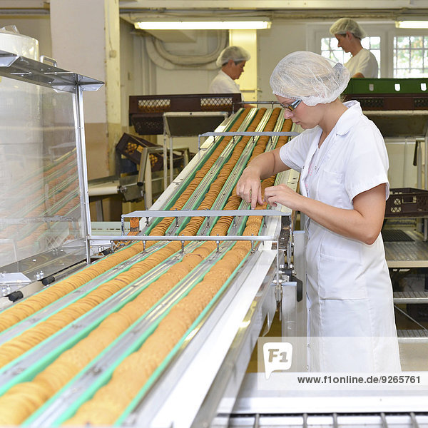 Deutschland  Sachsen-Anhalt  Frau kontrolliert Kekse in der Produktionslinie einer Backfabrik