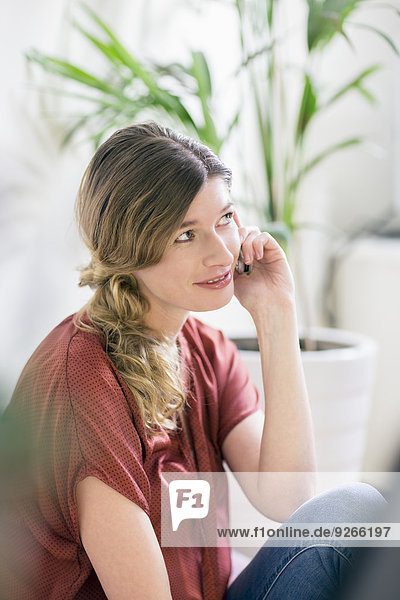 Porträt einer lächelnden Frau beim Telefonieren zu Hause
