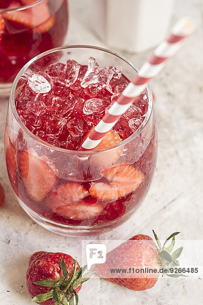 Glas eisgekühlter roter Früchtetee mit geschnittenen Erdbeeren und zerstoßenem Eis